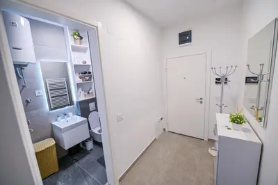 a white bathroom with a sink and a toilet at Apartman City Charm in Banja Luka