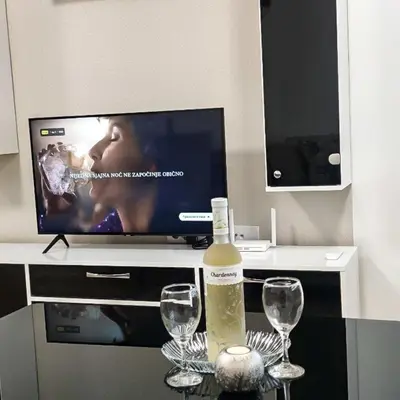 a bottle of wine sitting on a table with two glasses at Apartman Venecija De Lux in Banja Luka
