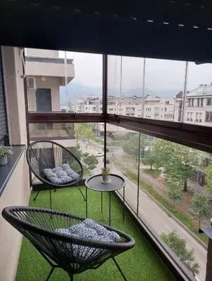 a balcony with two chairs and a table in front of a window at Apartman Venecija De Lux in Banja Luka