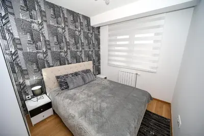 a bedroom with a bed and a black and white wall at Apartman Venecija De Lux in Banja Luka
