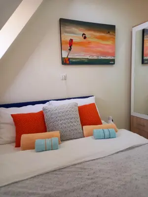 a bed with colorful pillows and a painting on the wall at Ena Apartment in Tuzla