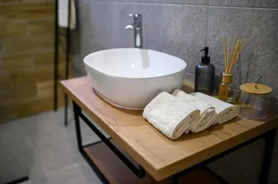 a bathroom with a sink and towels on a wooden table at Apartman UMA in Bihać