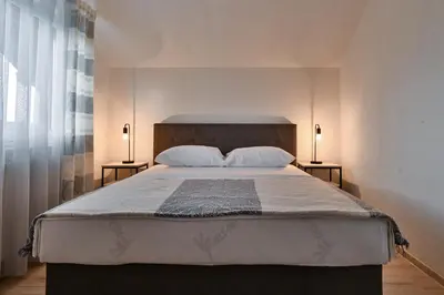 a bedroom with a large bed with two lamps on two tables at Apartman UMA in Bihać