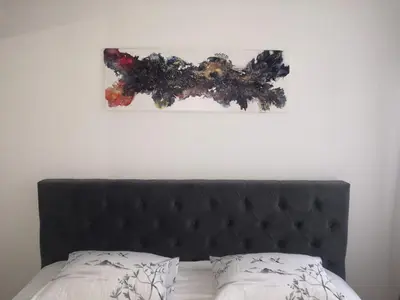 a bed with a black headboard and a painting on the wall at Apartman Deni in Travnik