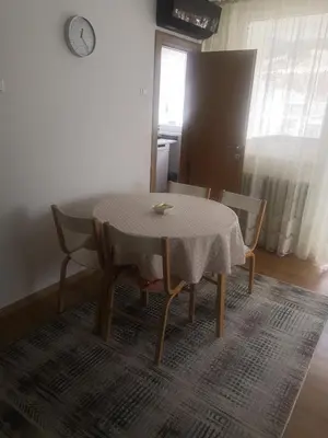 a table and chairs in a room with a table and a clock at Apartman Deni in Travnik