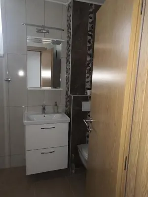 a bathroom with a sink and a toilet and a door at Apartman Deni in Travnik