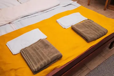 a bed with two towels on a yellow blanket at Domaćinska Kuća Banja Luka in Banja Luka