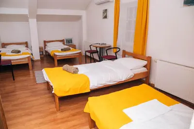 a room with three beds and a table at Domaćinska Kuća Banja Luka in Banja Luka
