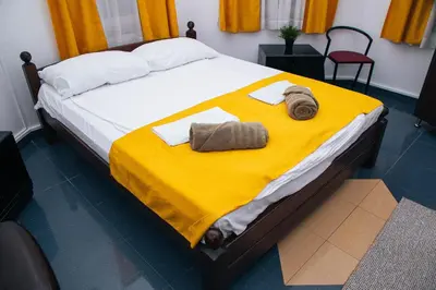 a bed with a yellow blanket and towels on it at Domaćinska Kuća Banja Luka in Banja Luka