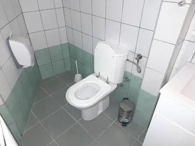 a small bathroom with a toilet and a trash can at Domaćinska Kuća Banja Luka in Banja Luka