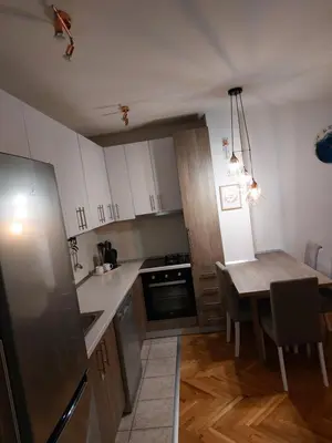 a kitchen with white cabinets and a table and a dining room at Stan na dan Banja luka in Banja Luka