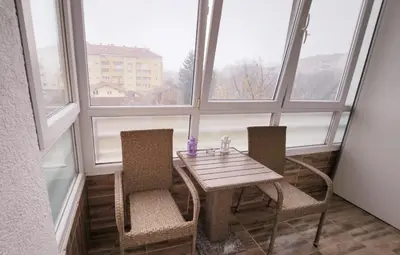 a table and two chairs in a room with windows at Stan na dan Banja luka in Banja Luka