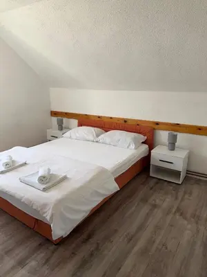 a bedroom with a large bed with white sheets at Apartman OGNJIŠTE in Kupres