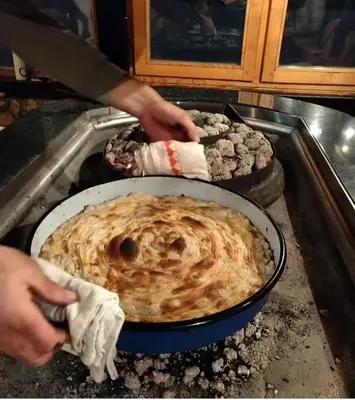 a person is preparing food in a pan at Apartman OGNJIŠTE in Kupres