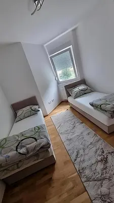 a attic room with two beds and a window at Visoko Prime Residence in Visoko