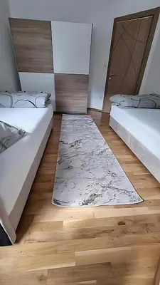 two beds in a room with a rug on the floor at Visoko Prime Residence in Visoko