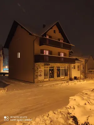 a large building in the snow at night at Guesthouse Kusić in Kupres