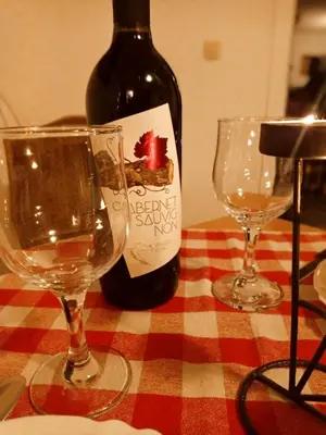 a bottle of wine and two wine glasses on a table at Guesthouse Kusić in Kupres