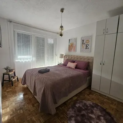 a bedroom with a large bed with purple sheets at FRIENDLY HOME in Tuzla