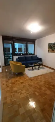 a living room with a blue couch and a wooden floor at Apartman B&D in Tuzla