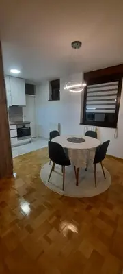 a living room with a table and chairs and a kitchen at Apartman B&D in Tuzla