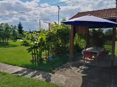 a patio with a table and an umbrella at Blossom Cottage - ''Green Tourism'' in Laktaši