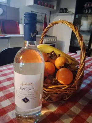 a bottle of wine sitting next to a basket of fruit at Blossom Cottage - ''Green Tourism'' in Laktaši