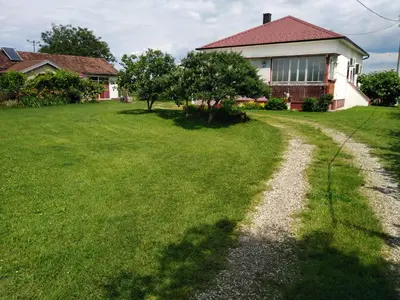 a house with a grass yard with a gravel road at Blossom Cottage - ''Green Tourism'' in Laktaši