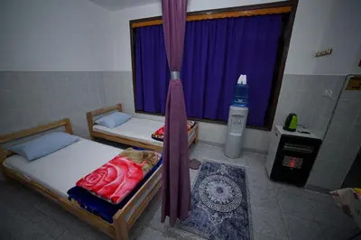 a room with two beds and a window with purple curtains at Prenoćište KRAJINA in Velika Kladuša