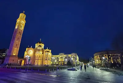 a large building with a clock tower at night at Riverside Panorama Apartment 1 near City Center Brko 1 in Banja Luka