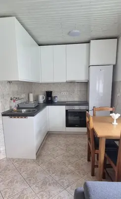 a kitchen with white cabinets and a wooden table at Riverside Panorama Apartment 1 near City Center Brko 1 in Banja Luka
