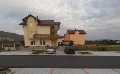 a large house with two cars parked in a parking lot at Čičak in Livno