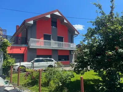 a red house with a car parked in front of it at Apartman Ćuprija in Cazin