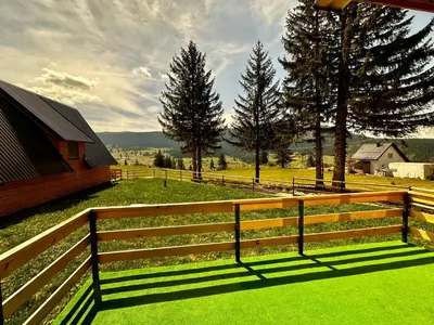 a wooden fence in front of a field with trees at Vlasic Odmor - Villa Krajina IV & jacuzzi in Vlasic