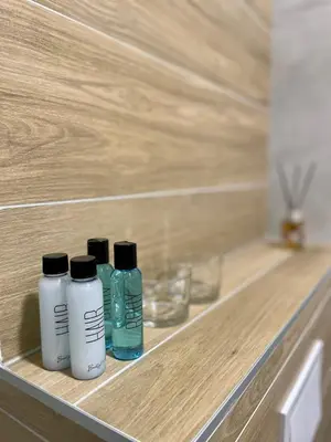 three bottles of liquids sitting on a wooden shelf at Apartment City Park in Banja Luka