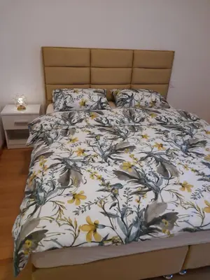 a bed with a blanket with flowers on it at Apartman Lena in Banja Luka
