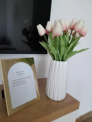 a white vase with pink flowers on a table at Apartman Lena in Banja Luka
