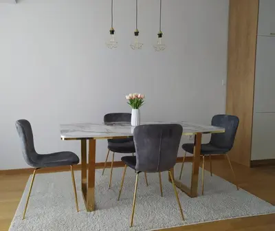 a dining room table with chairs and a vase of flowers on it at Apartman Lena in Banja Luka