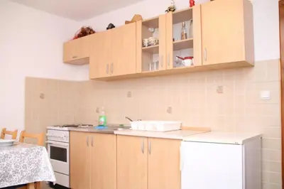 a kitchen with wooden cabinets and a white refrigerator at Apartman Vuvuzela in Kupres