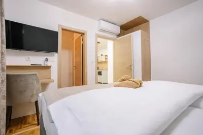 a bedroom with a white bed and a flat screen tv at Apartments Hana City Center in Livno