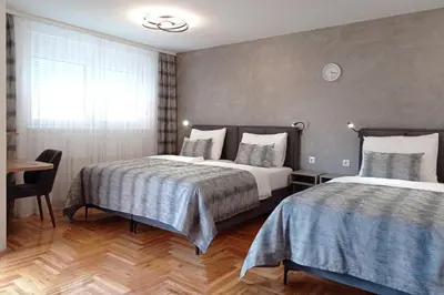 a hotel room with two beds and a table at Apartments Hana City Center in Livno