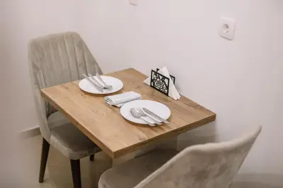 a wooden table with white plates and silverware on it at Apartments Hana City Center in Livno