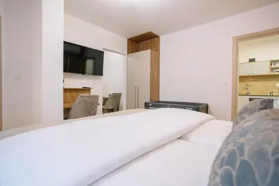 a bedroom with a white bed and a tv at Apartments Hana City Center in Livno