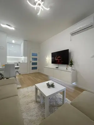 a white living room with a table and a tv at Apartman Blok 51 in Banja Luka