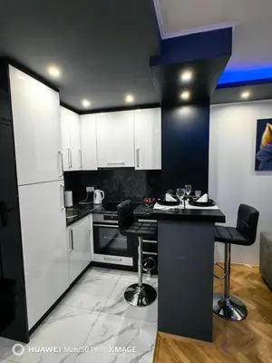a kitchen with white cabinets and black counter tops at Apartmani AMONA STAN NA DAN in Doboj