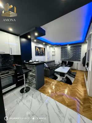 a kitchen and living room with a counter and a table at Apartmani AMONA STAN NA DAN in Doboj
