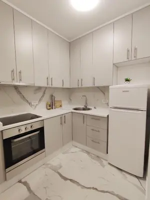 a kitchen with white cabinets and a sink and a refrigerator at Apartman 7 Ladies in Banja Luka