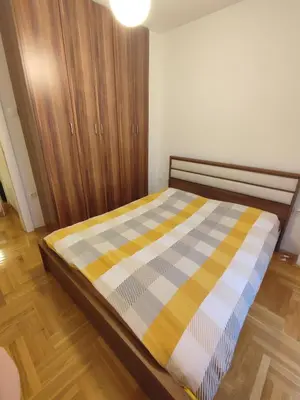 a bed in a room with a wooden cabinet at Mila apartman in Banja Luka
