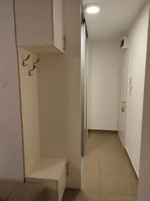 a hallway with white walls and a bench and a door at Mila apartman in Banja Luka