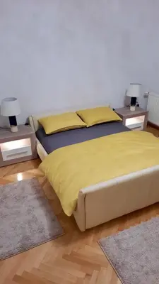 a bedroom with a bed with yellow sheets and two tables at Nova DOM in Banja Luka